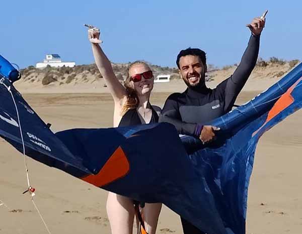 Débutante heureuse avec son aile de kitesurf et son coach.