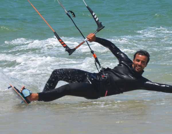 Instructeur de kitesurf qui rase l'eau avec le sourire.